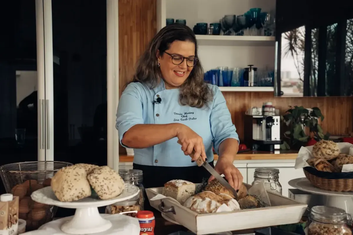 Chef Vanda Hering cortando pães low carb em uma bandeja na cozinha